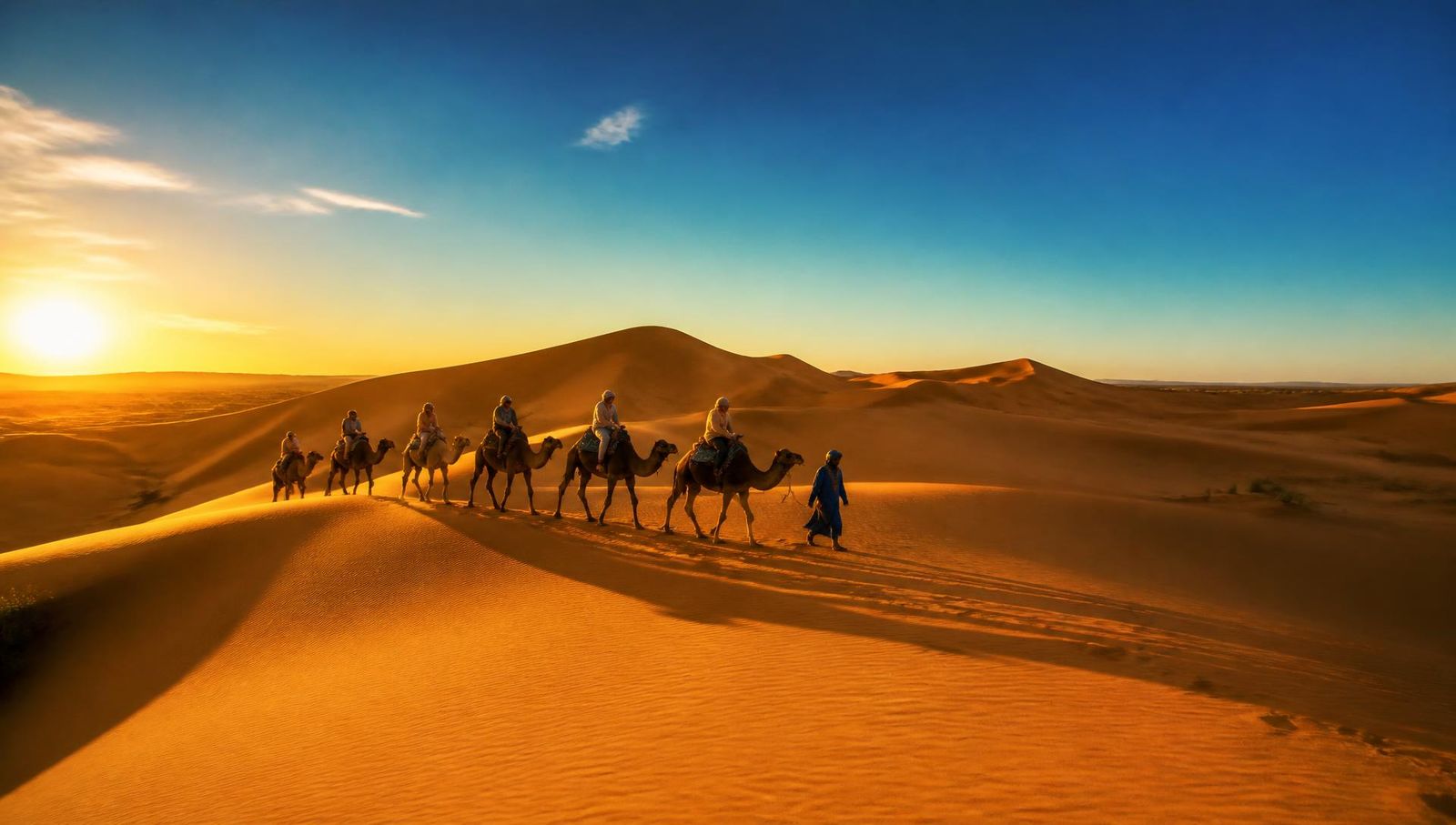 Caravana de camelos atravessando as dunas do Saara ao pôr do sol